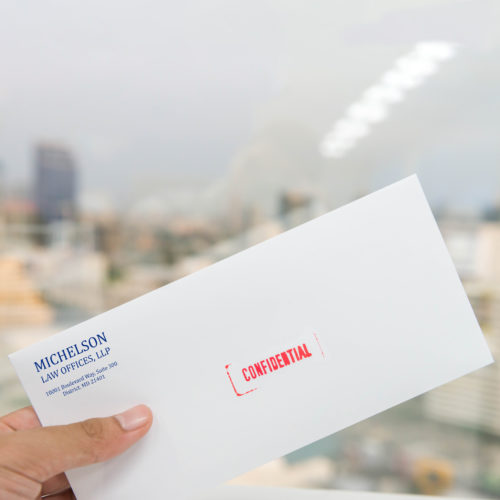 Hand is holding the white envelope with red confidential rubber stamp